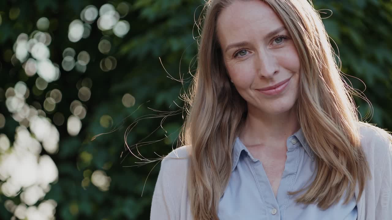 Professional businesswoman standing confidently in green park setting, radiating optimistic energy and success through serene, elegant posture during bright, sunny daytime moment