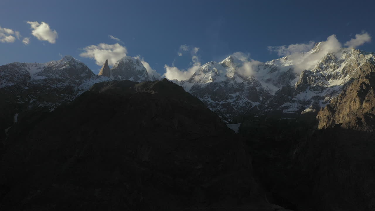 Dramatisk droneoptagelse af Tupopdan Peak, Passu Cones i Hunza, Pakistan, sneklædte bjergtoppe med stejle klipper, høj vidvinkel luftoptagelse.