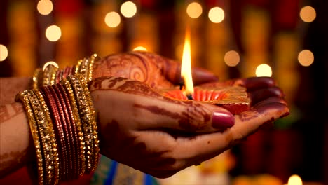 woman with traditional bangles holding oil lamp on the occasion of diwali puja - bokeh effect
