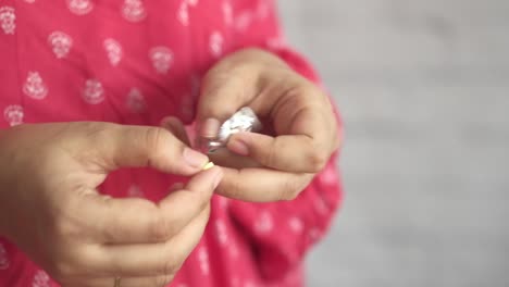 woman taking a yellow pill from a blister pack