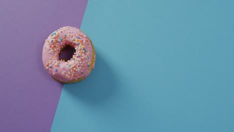 Video-Von-Donut-Mit-Zuckerguss-Auf-Violettem-Und-Blauem-Hintergrund