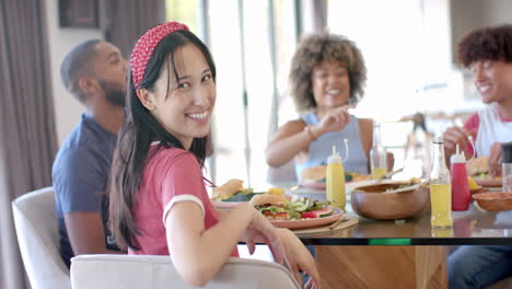 smiling woman with diverse friends enjoying meal together, having fun and laughing