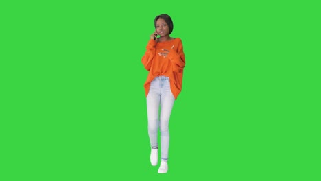 emotional african american woman in bright jumper talking on the phone while walking on a green screen, chroma key