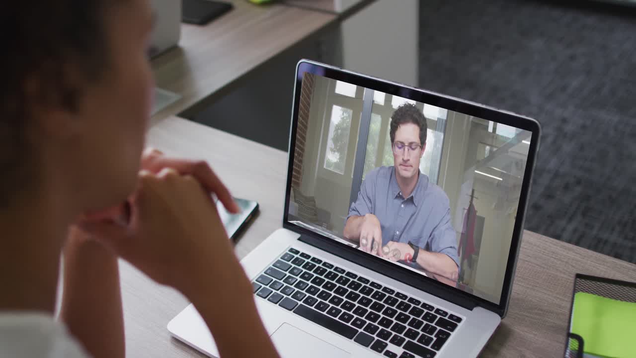 mujer afroamericana haciendo una videollamada en una computadora portátil con un colega masculino en la oficina