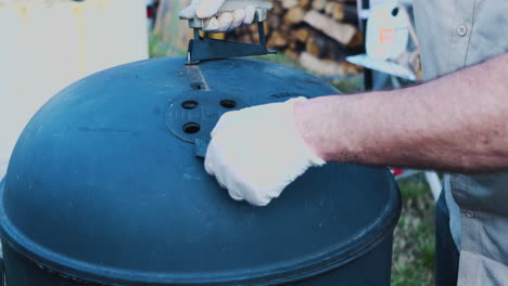 the lid of a bbq pit being placed over a cooking rack of ribs