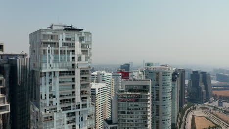 Forward-fly-above-group-of-skyscrapers.-Camera-tilt-down-on-multilane-road-with-roundabout.-Mexico-City,-Mexico.