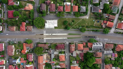 Birds-eye-view-of-a-tram-station-with-a-tram-passing-by-in-a-suburb-area