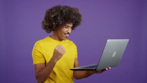 a man with afro hair shows excitement and happiness while using a laptop