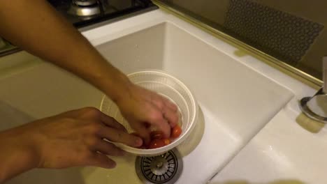 persona lavando tomates en un fregadero de la cocina