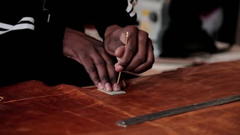 a man uses a stencil to cut out shapes from a large piece of leather to make leather goods