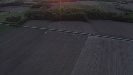 Filmische-Aufnahmen-Des-Sonnenuntergangs-Und-Im-Perfekten-Moment-Ein-Auto,-Das-Die-Straße-Passiert