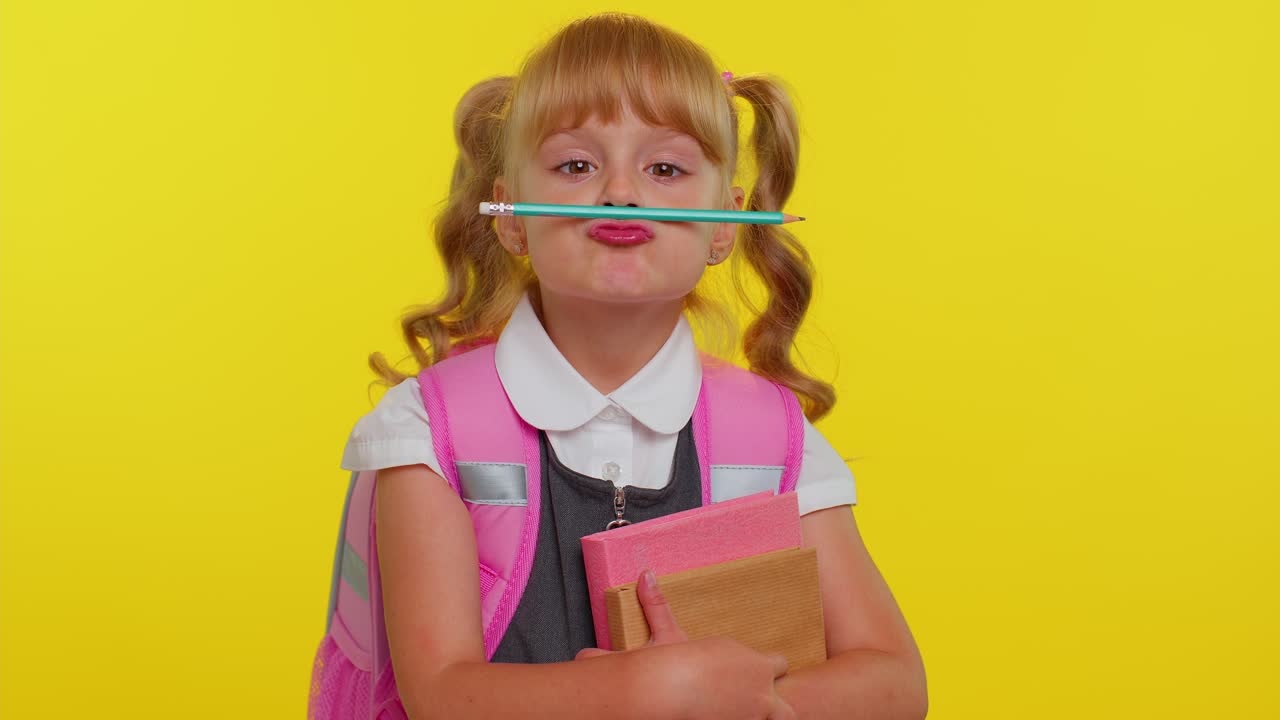 chico gracioso chica de escuela primaria haciendo expresiones faciales tontas juguetonas jugando con la pluma