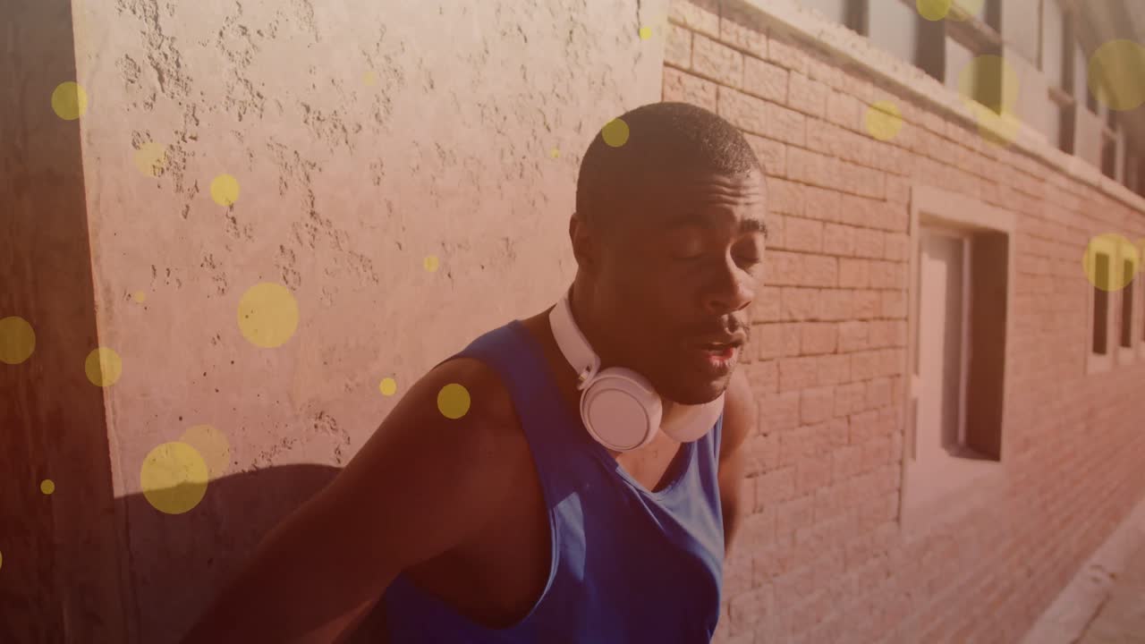 Yellow spots floating against tired african american fit man taking a break from running