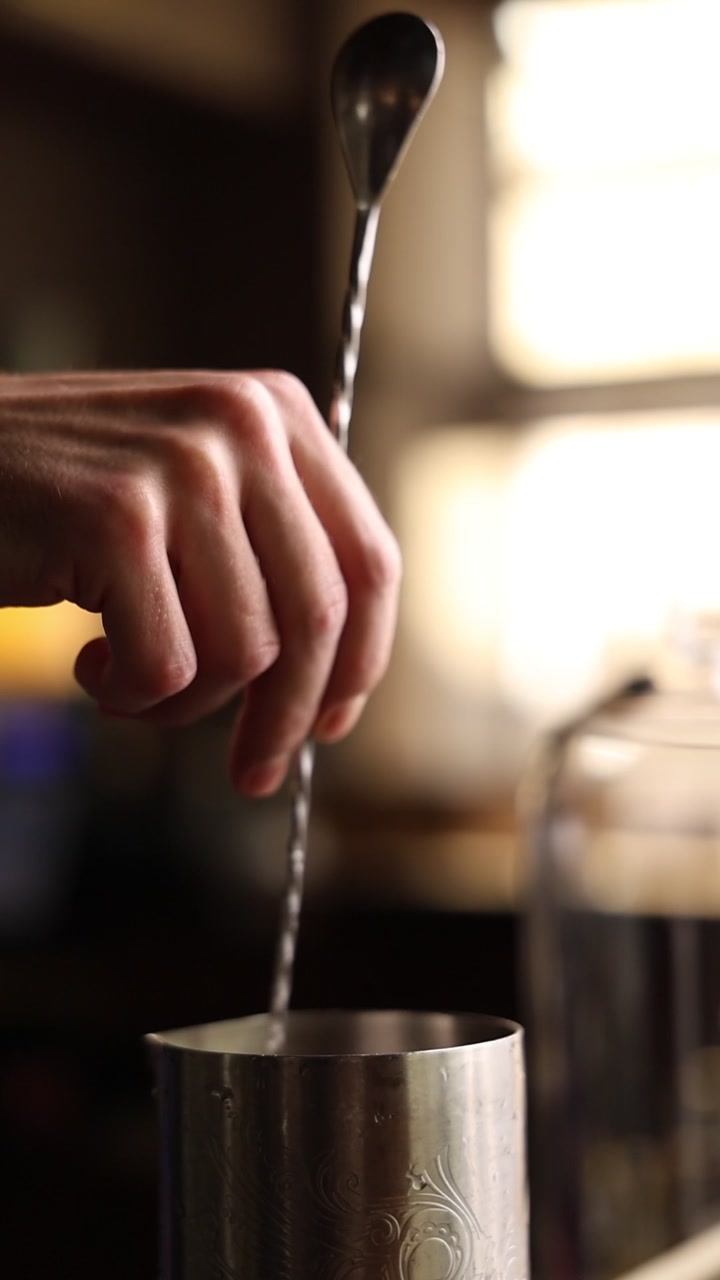 Barman che mescola un cocktail in un mixing tin di metallo