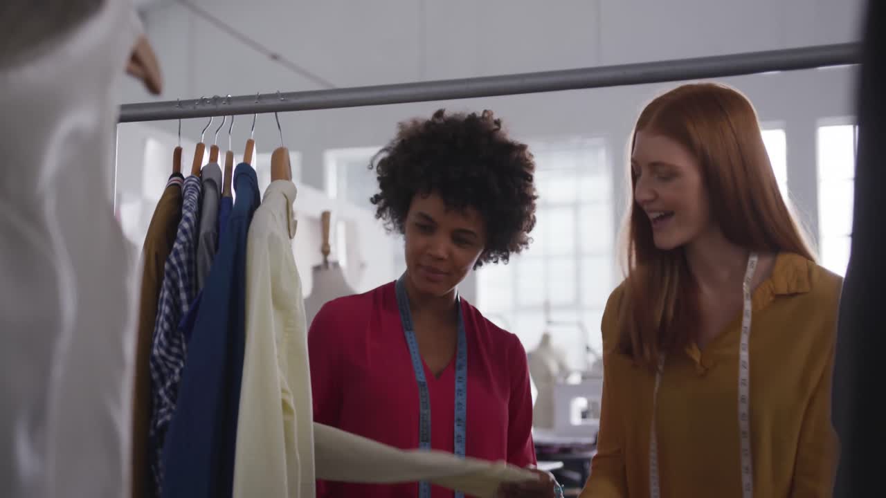 Two women choosing clothes in fashion office