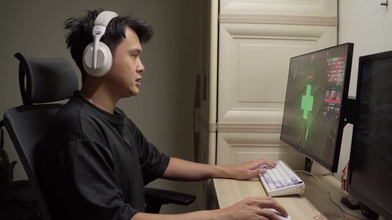 Giovane uomo concentrato a giocare a un videogioco sparatutto in prima persona alla sua postazione da scrivania a casa