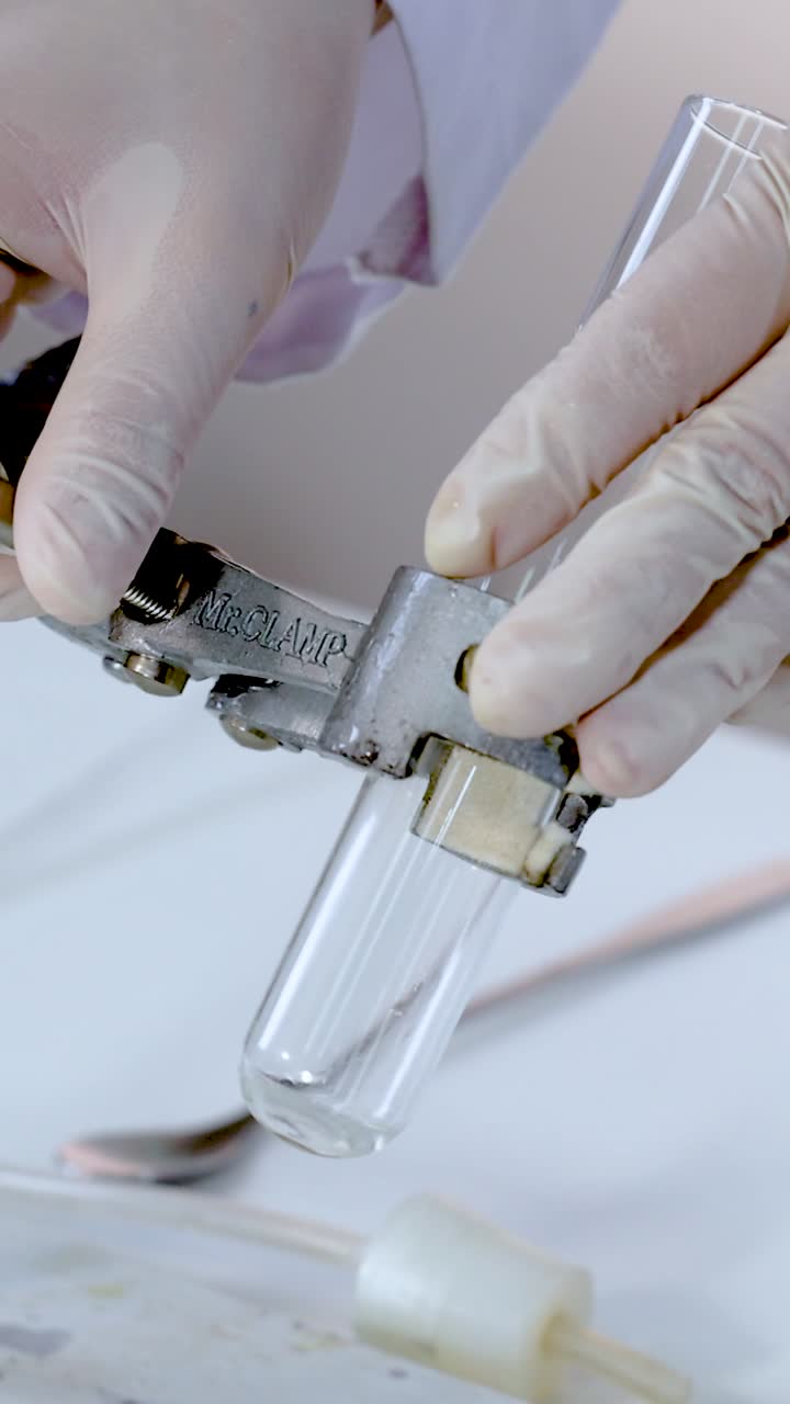 manos manipulando la pinza del tubo de ensayo en un entorno de laboratorio