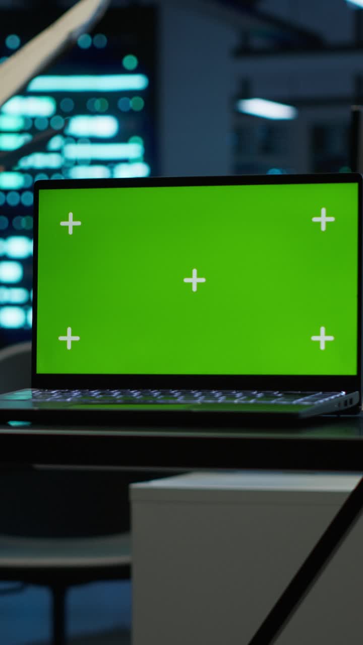 Laptop with Green Screen Display in Dark Tech Office