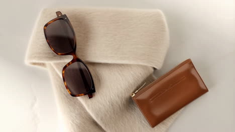 fashion accessories flat lay with sunglasses, knitwear, and leather pouch