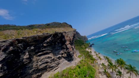 aerial around huge cliffs over the beach of fronton in the dominican republic, fpv