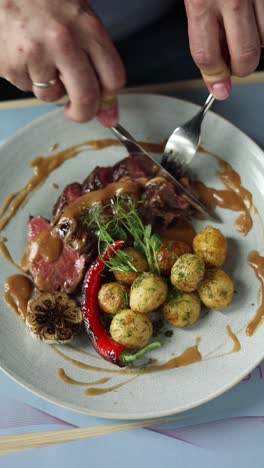 person eating a steak dinner with potatoes and gravy