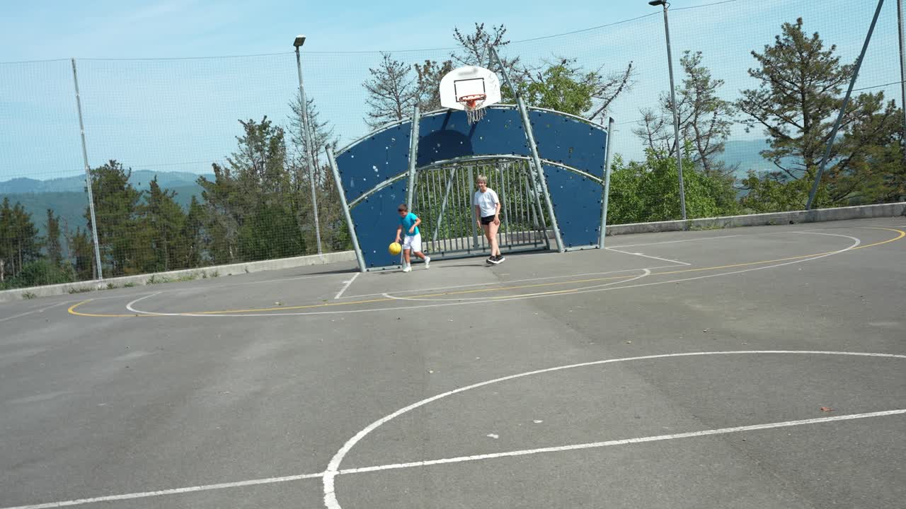 Due bambini che giocano con una palla su un campo sportivo all'aperto
