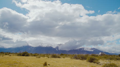 a medium sized van drives on a highway with snow capped mountains in the background