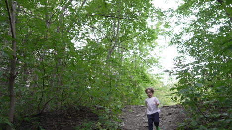 child running in outdoor garden. kid walking towards camera in forest. happy young boy walking down the slope in forest alone.
