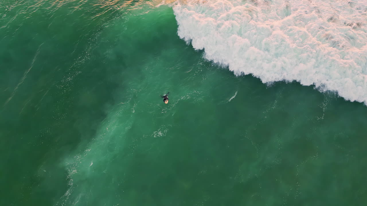 Un surfista sdraiato nell'acqua turchese del mare si gode il suo hobby estivo. Schiuma di un'onda impetuosa.