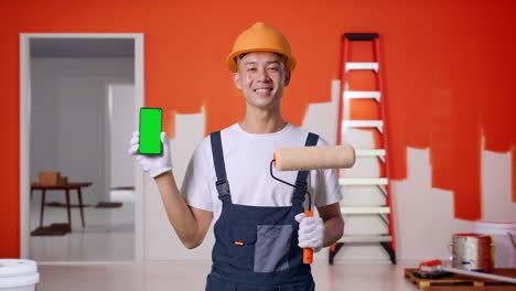 trabajador de la construcción sosteniendo un teléfono y un rodillo de pintura
