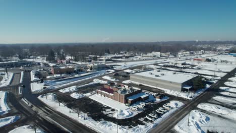Aerial-view-of-small-american-town,-suburb-area-covered-in-snow-in-sunny-winter-day