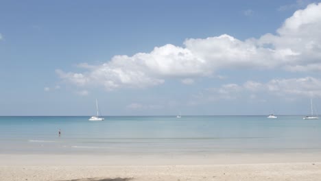 沙灘上有幾艘遊艇在海上, 白色的沙子和波浪從平靜的海在陽光白天