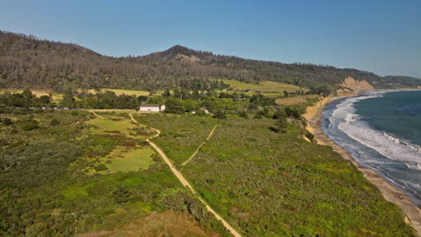 Año-Nuevo-State-Park-California-Aerial-v2-flyover-long-stretched-cove-beach-capturing-strong-and-powerful-waves-crashing-the-shore,-coastal-landform-and-vegetations---Shot-with-Mavic-3-Cine---May-2022