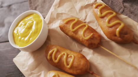 video of corn dogs with dip on a wooden surface