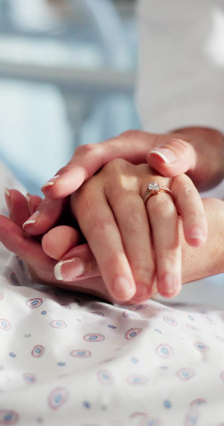 Primo piano di una persona che conforta un paziente tenendogli la mano in ospedale