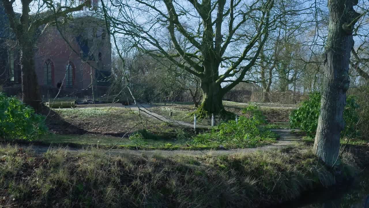 Fredelig parkscene med historisk bygning og nøgne træer