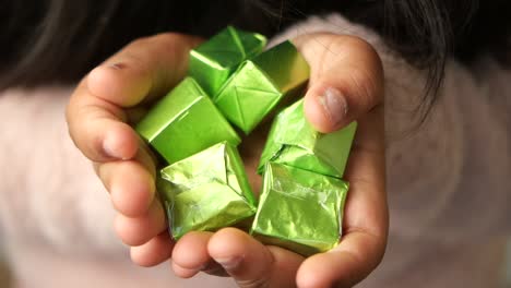 child's hands holding green foil packets