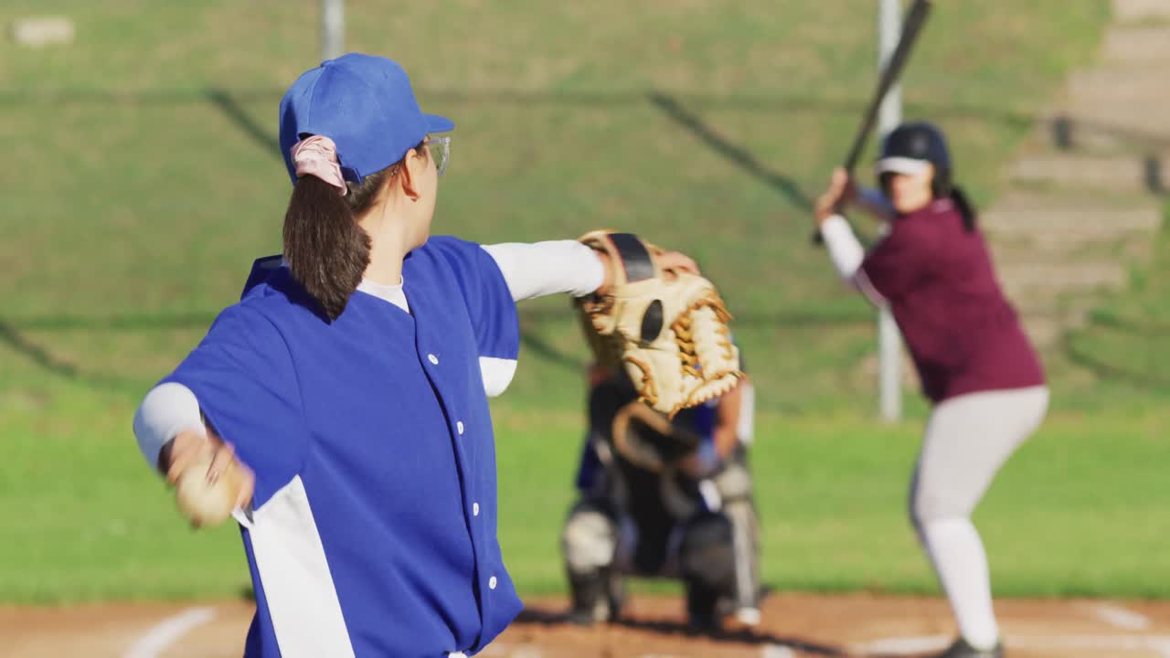 Gruppo eterogeneo di giocatrici di baseball in azione sul campo, palla lanciata presa dal ricevitore.