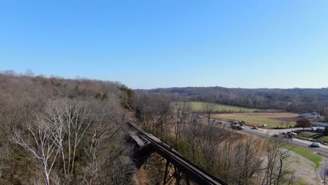 aerial shot of railroad tracks winding out of a forest and on to the pope lick trestle in louisville kentucky