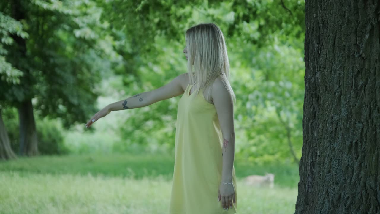 아름다운 젊은 소녀가 자유의 춤을 추고 있습니다. 여름 공원에서 뒷면에 나무가 있습니다.