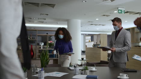 diverse corporate team meeting wearing face mask in office table. covid concept.