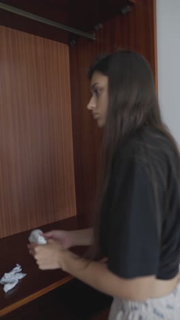 woman organizing clothes in a wooden wardrobe