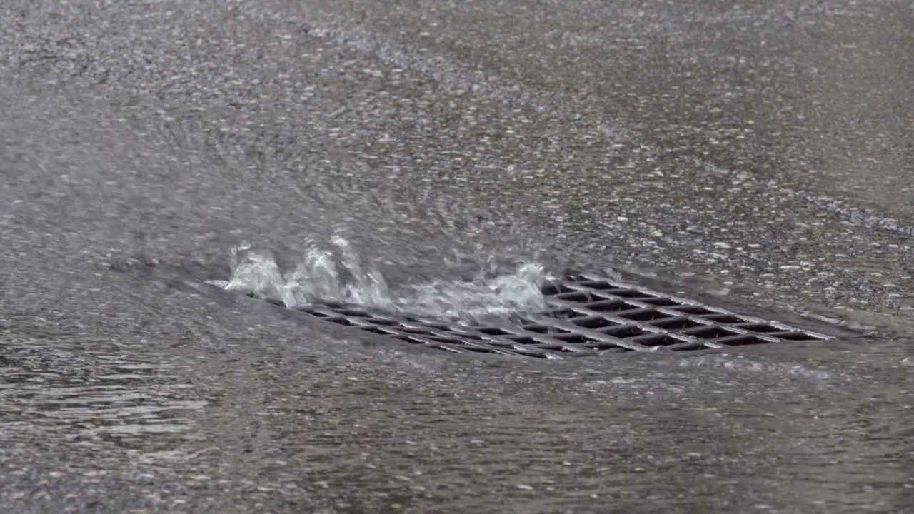 L'acqua scorre in un tombino stradale, prevenendo così gravi allagamenti.