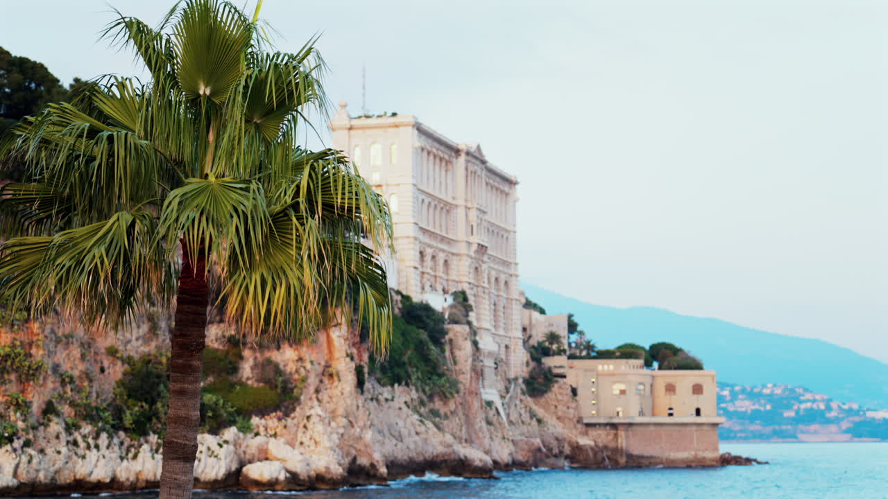 View of the The Oceanographic Museum of Monaco on the shore with the mountains on the background