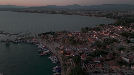 aerial view circling illuminated side old town waterfront neighbourhood and mediterranean marina at sunset