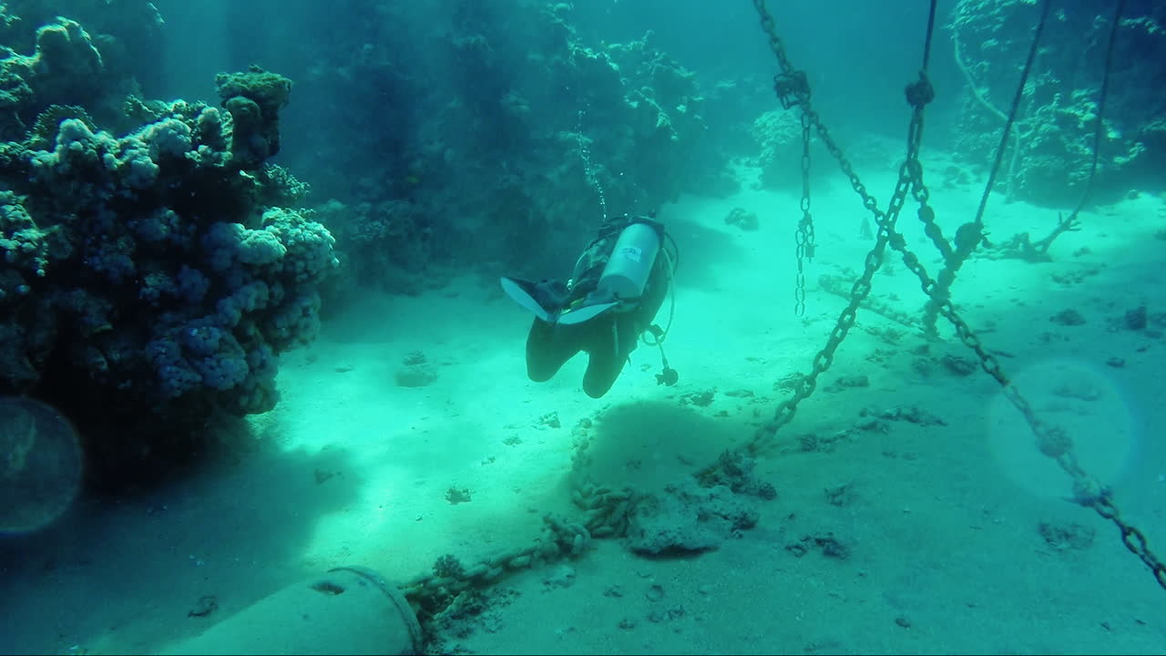 buzo nada bajo el agua cerca de las cadenas de anclaje
