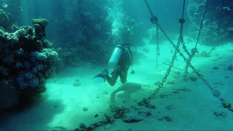 Diver-Underwater-Swims-Near-The-Anchor-Chains