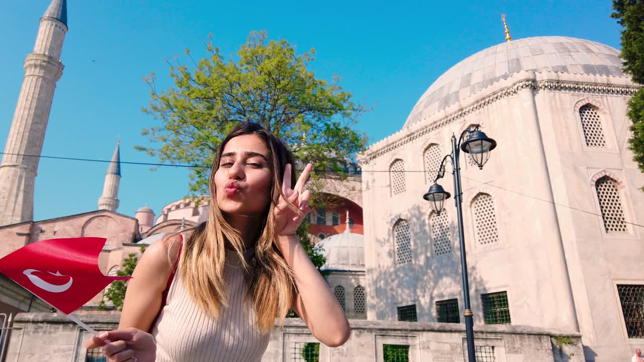 Cámara lenta: Hermosas jóvenes ondeando la bandera turca frente a un edificio antiguo en Estambul, Turquía. Concepto de viaje.