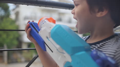 footage of a little caucasian boy playing with a water gun toy