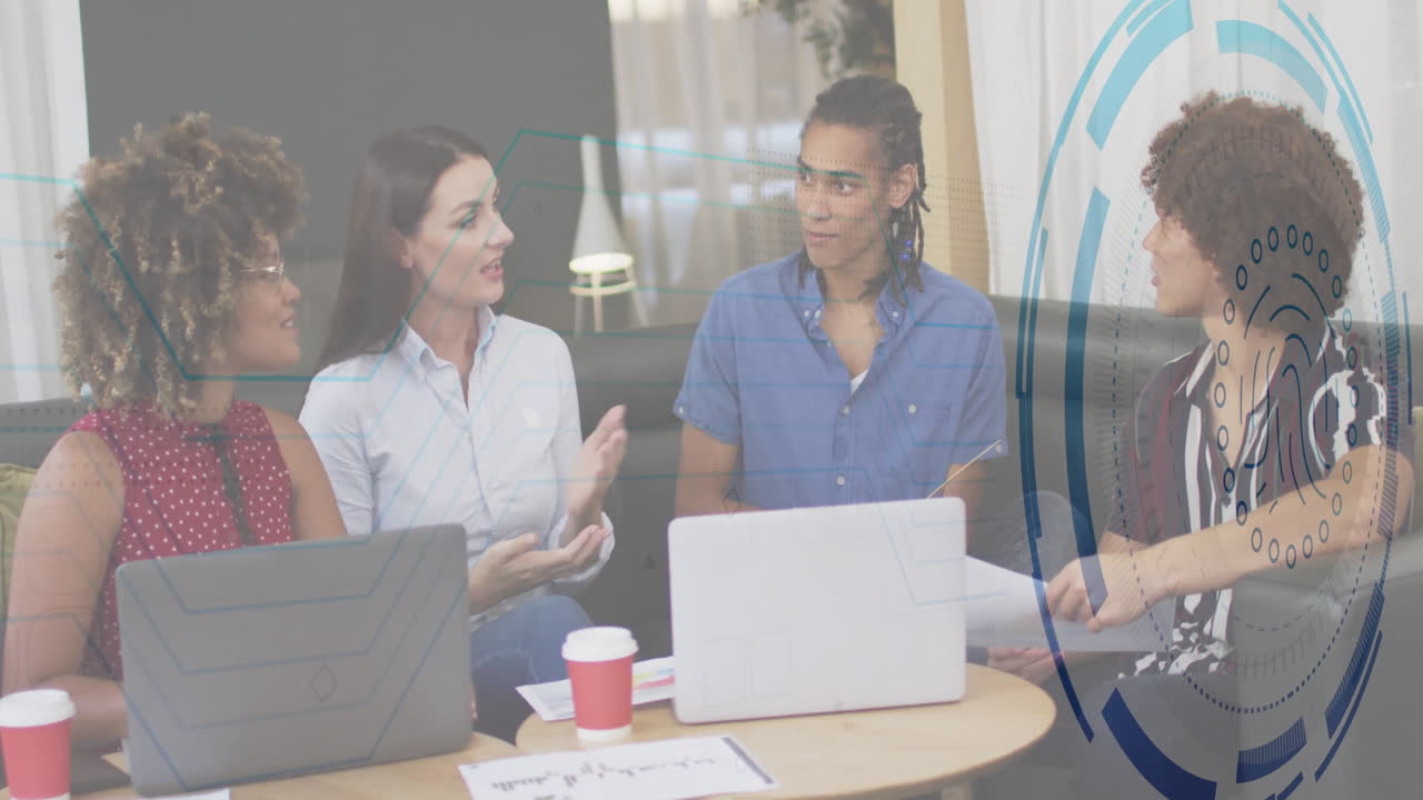 Team collaborating around laptops in business meeting, displaying animated data charts and icons